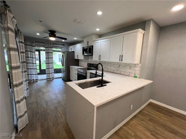 kitchen with sink, appliances with stainless steel finishes, white cabinetry, dark hardwood / wood-style flooring, and kitchen peninsula