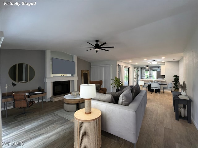 living room featuring wood-type flooring, lofted ceiling, and ceiling fan