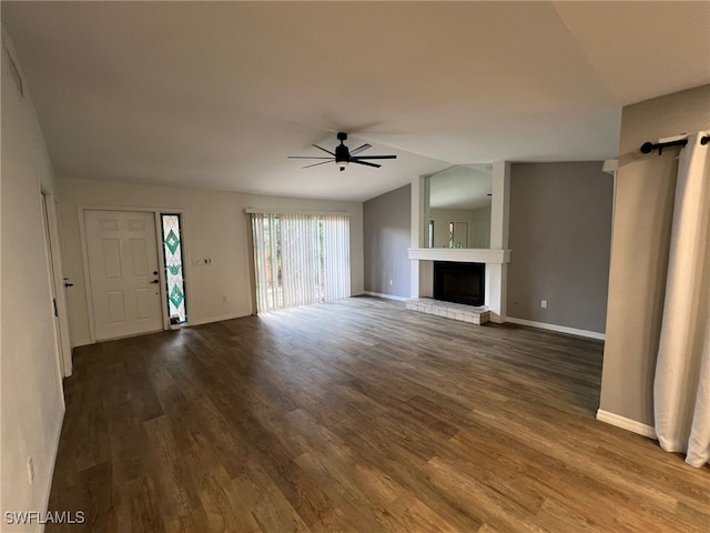 unfurnished living room with dark hardwood / wood-style flooring, lofted ceiling, a large fireplace, and ceiling fan