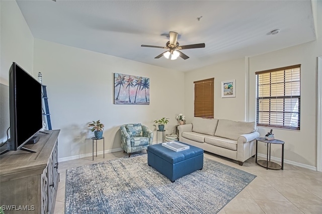 living room with light tile patterned flooring, a ceiling fan, and baseboards