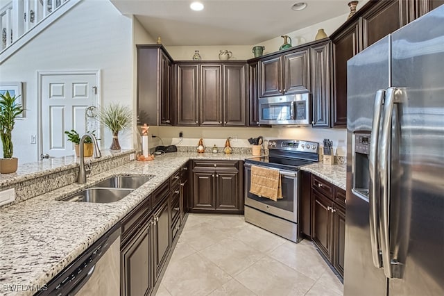 kitchen with appliances with stainless steel finishes, recessed lighting, a sink, and light stone counters