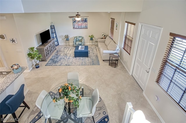 living area featuring a wealth of natural light, ceiling fan, baseboards, and light tile patterned floors