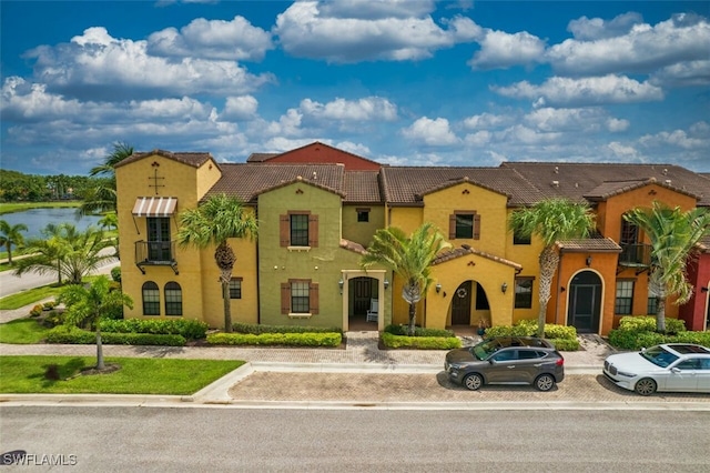 view of front of house with a water view, a tiled roof, and stucco siding