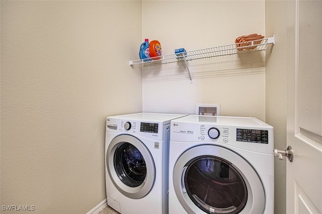 clothes washing area featuring laundry area, baseboards, and washing machine and clothes dryer