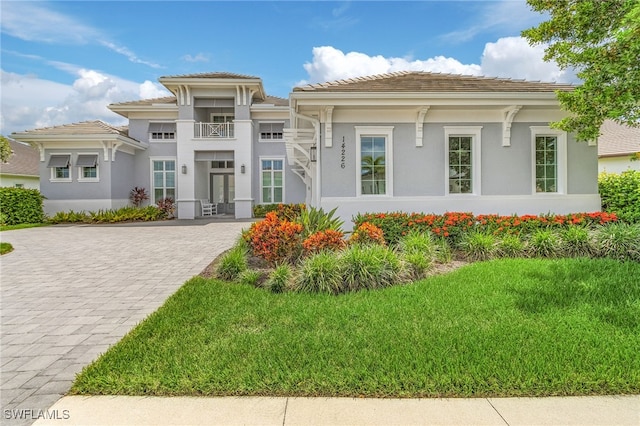 prairie-style home featuring stucco siding, a tiled roof, and decorative driveway