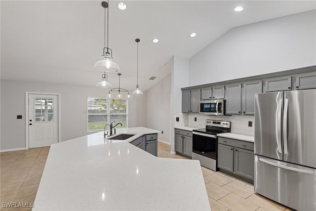 kitchen featuring appliances with stainless steel finishes, gray cabinetry, vaulted ceiling, sink, and hanging light fixtures