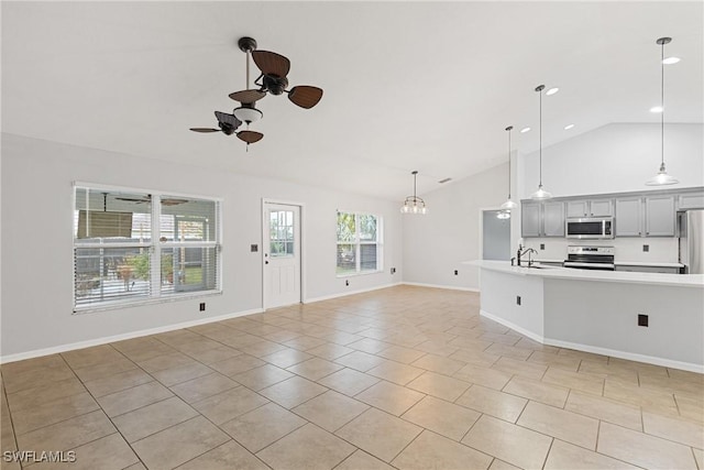 unfurnished living room with ceiling fan with notable chandelier, light tile patterned flooring, sink, and vaulted ceiling