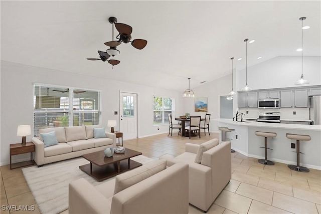 tiled living room with sink, ceiling fan with notable chandelier, and lofted ceiling