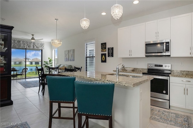 kitchen with a wealth of natural light, stainless steel appliances, sink, and ceiling fan with notable chandelier