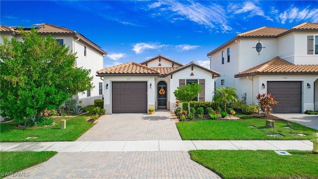 mediterranean / spanish-style house featuring stucco siding, a tile roof, decorative driveway, and a front yard