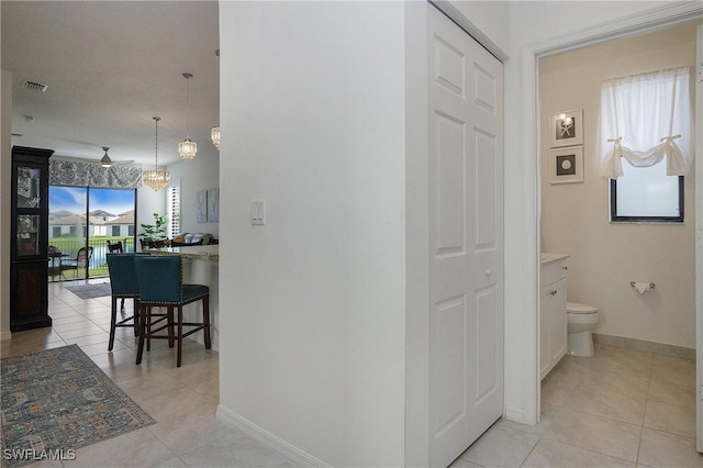 corridor with baseboards and light tile patterned floors