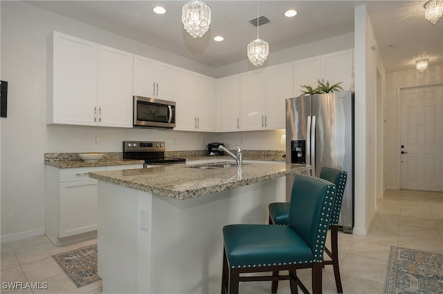 kitchen with white cabinetry, stainless steel appliances, an inviting chandelier, sink, and a center island with sink