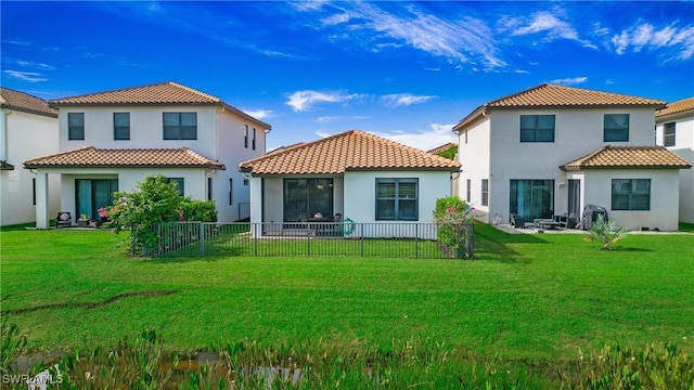 rear view of house featuring a lawn, a fenced backyard, a tiled roof, and stucco siding