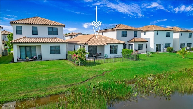 rear view of house with central AC unit and a yard