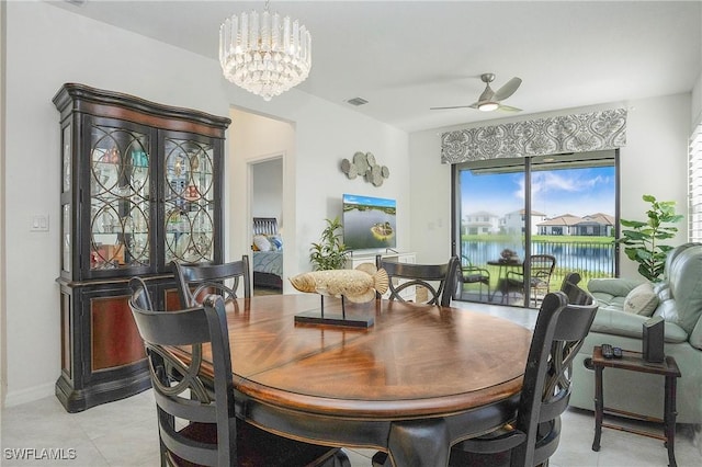 dining room featuring light tile patterned floors, a water view, visible vents, and ceiling fan with notable chandelier