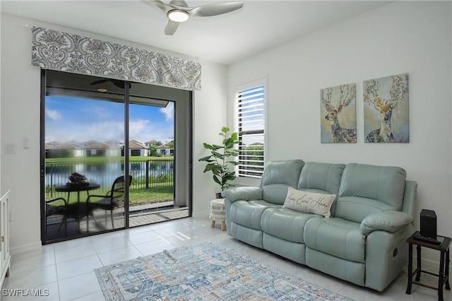 living room with ceiling fan, light tile patterned floors, and a water view