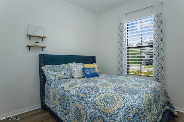 bedroom with multiple windows and dark hardwood / wood-style floors