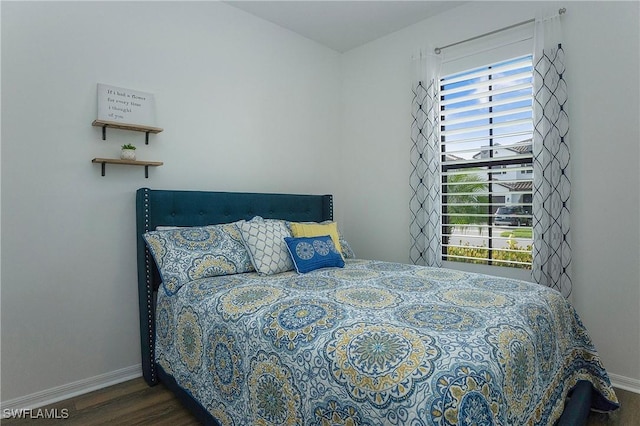 bedroom featuring baseboards, wood finished floors, and multiple windows