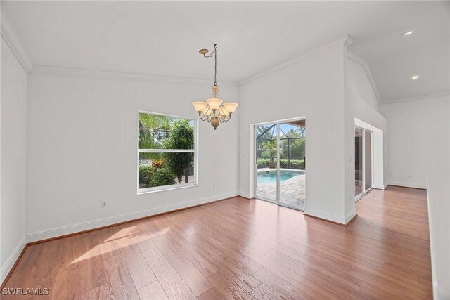 interior space featuring wood-type flooring, vaulted ceiling, an inviting chandelier, and ornamental molding