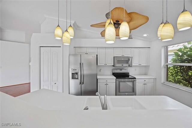 kitchen featuring crown molding, stainless steel appliances, hanging light fixtures, and vaulted ceiling