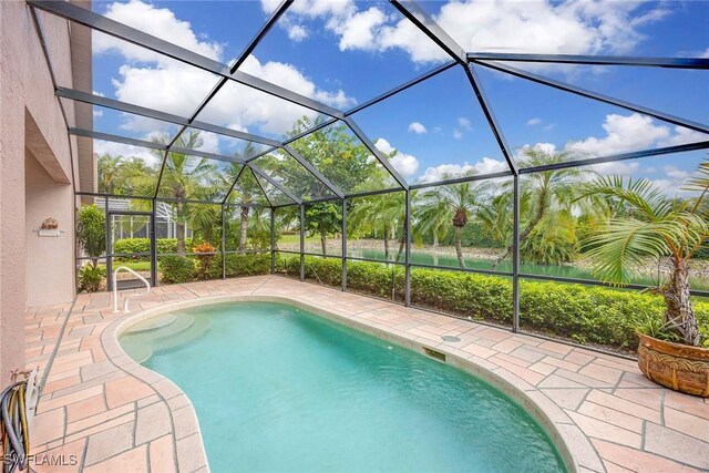 view of pool with glass enclosure and a patio