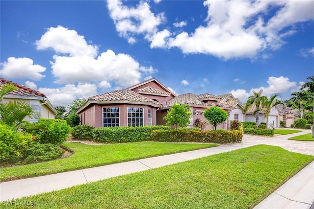 mediterranean / spanish-style home featuring a tiled roof, a front yard, stucco siding, a garage, and driveway