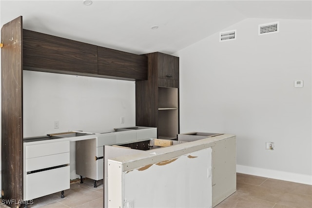 kitchen featuring lofted ceiling, dark brown cabinetry, white cabinetry, and light tile patterned flooring