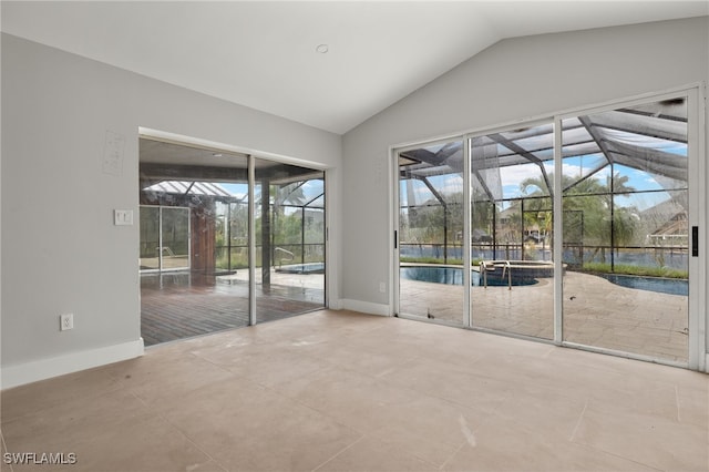 empty room with lofted ceiling, tile patterned flooring, and plenty of natural light