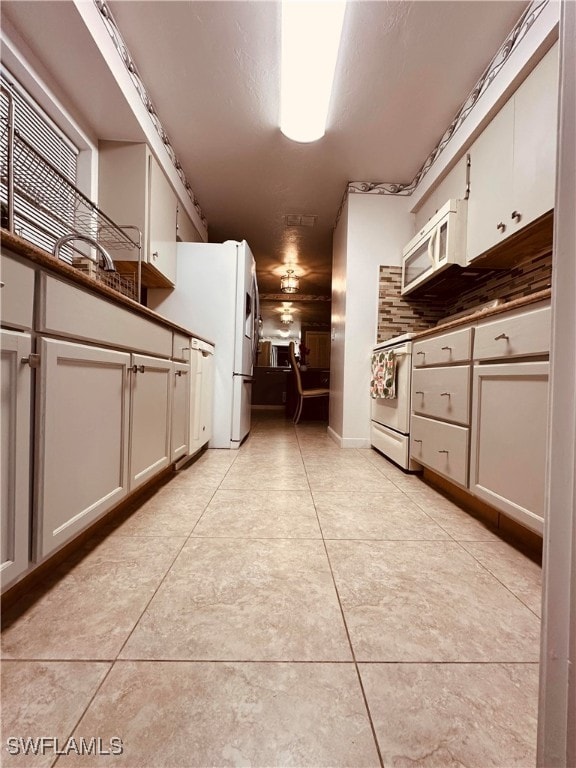 kitchen with white cabinetry, white appliances, and light tile patterned floors