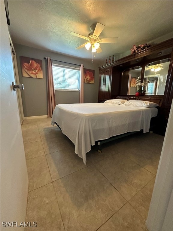 tiled bedroom featuring ceiling fan and a textured ceiling