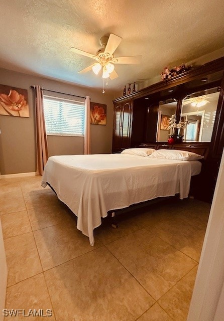 tiled bedroom featuring ceiling fan and a textured ceiling