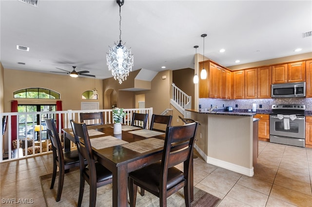 tiled dining area featuring ceiling fan with notable chandelier