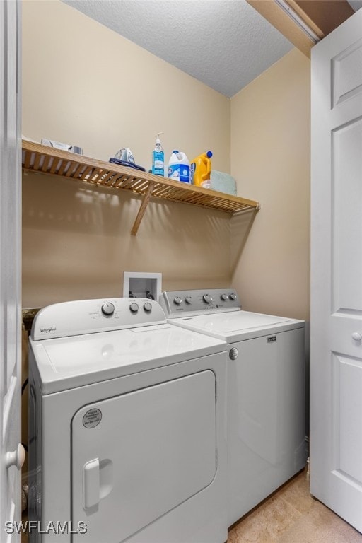 laundry area with a textured ceiling and washing machine and clothes dryer