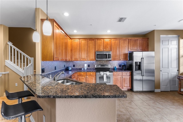 kitchen with a kitchen breakfast bar, kitchen peninsula, pendant lighting, stainless steel appliances, and sink