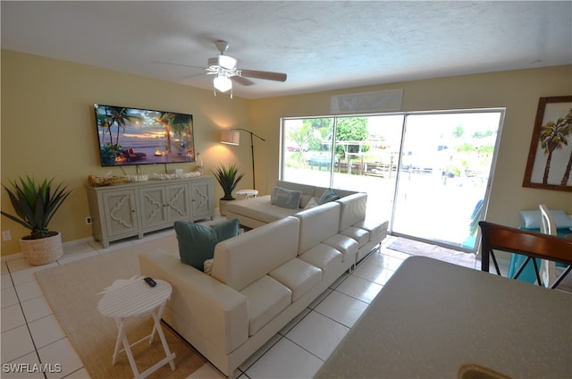 living room featuring a textured ceiling, a healthy amount of sunlight, light tile patterned floors, and ceiling fan