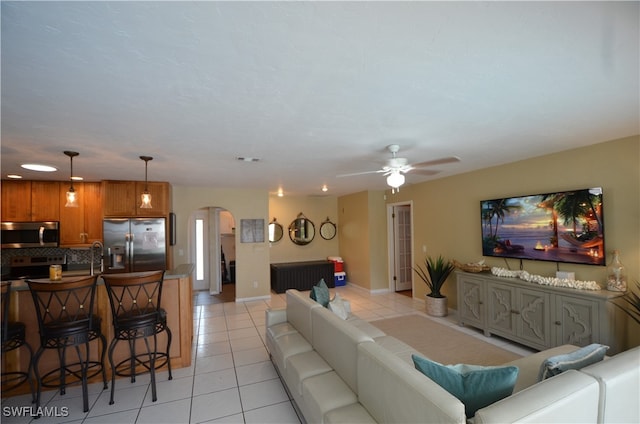 living room featuring ceiling fan, light tile patterned floors, and sink