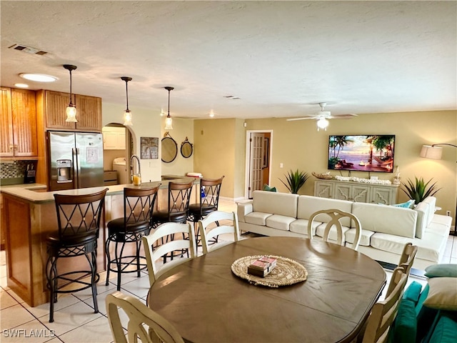 tiled dining space with a textured ceiling, sink, and ceiling fan