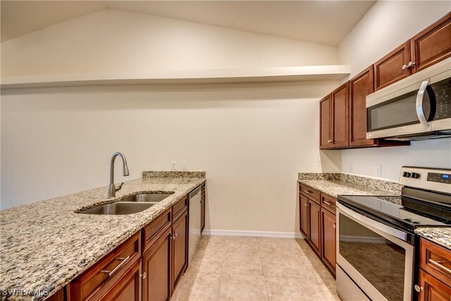 kitchen featuring appliances with stainless steel finishes, light stone counters, vaulted ceiling, and sink