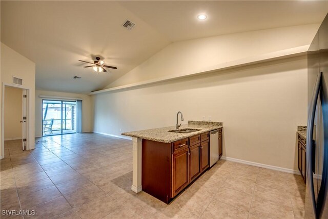 kitchen featuring vaulted ceiling, light stone countertops, stainless steel appliances, sink, and ceiling fan