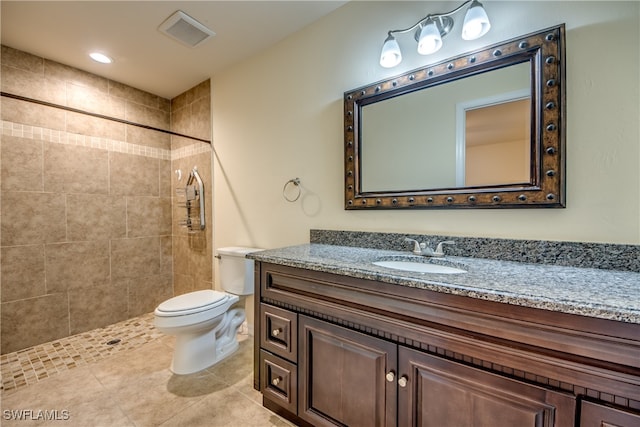 bathroom with tile patterned flooring, toilet, a tile shower, and vanity