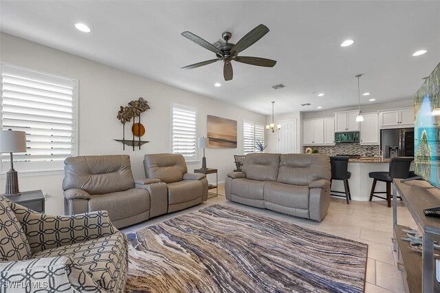 living room featuring ceiling fan with notable chandelier and light tile patterned floors