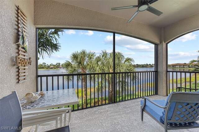 sunroom with a water view and ceiling fan