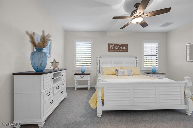 bedroom featuring multiple windows, ceiling fan, and dark colored carpet