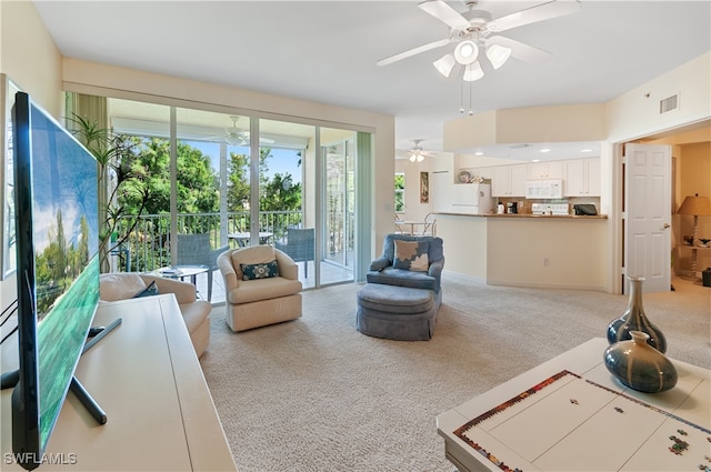 living room with ceiling fan, plenty of natural light, and light carpet