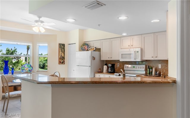 kitchen featuring white appliances, white cabinetry, kitchen peninsula, ceiling fan, and tasteful backsplash