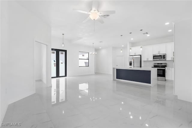 kitchen featuring a kitchen island with sink, pendant lighting, ceiling fan with notable chandelier, white cabinetry, and appliances with stainless steel finishes