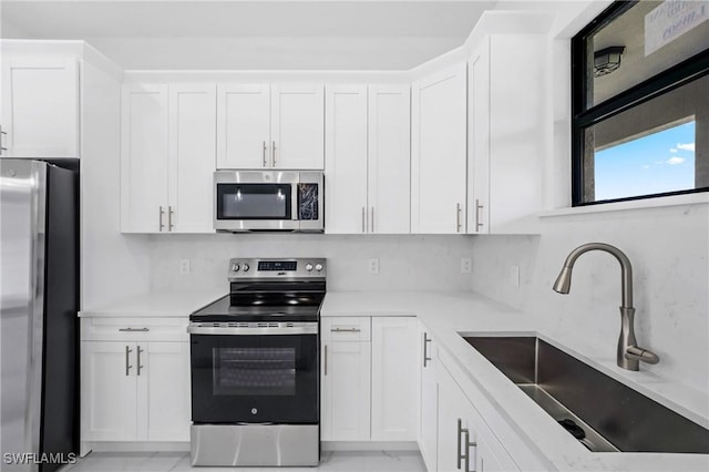 2602 73rd St W, Lehigh Acres, FL 33971 - kitchen with decorative backsplash, light countertops, stainless steel appliances, white cabinetry, and a sink