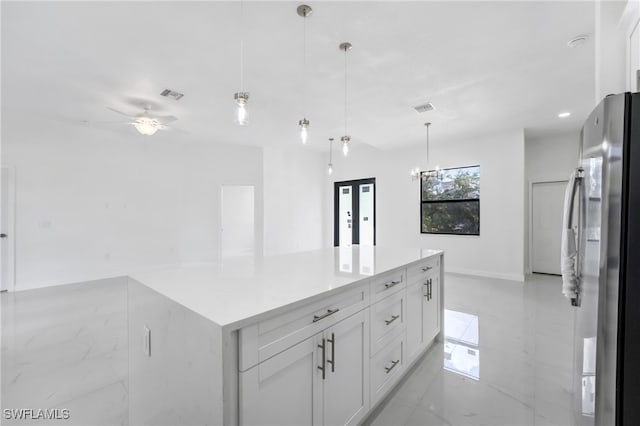 kitchen featuring stainless steel fridge, a kitchen island, plenty of natural light, and white cabinetry