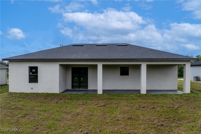 rear view of property with a lawn, a patio area, and central AC unit