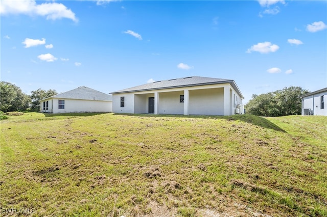 rear view of property featuring central air condition unit and a yard